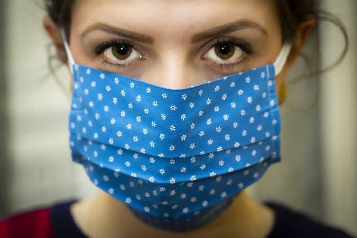 A woman protecting herself and others from covid with a blue face mask